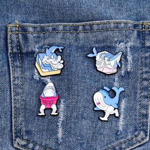 Creative 4-piece ocean enamel pin set featuring walking whales and sharks on denim background