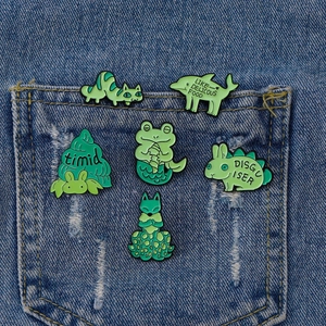 Set of 6 cute green enamel animal badges including cat and frog pinned on denim fabric