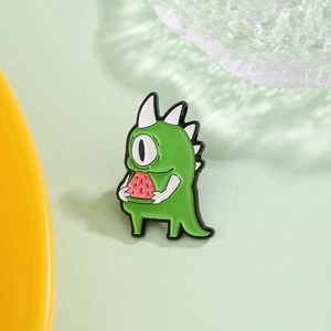 Cartoon green one-eyed monster enamel pin holding a watermelon slice with sharp horns