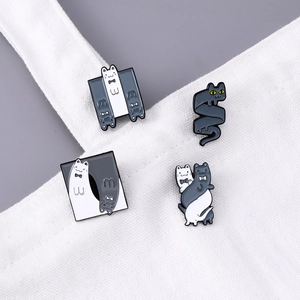 Set of four minimalist cartoon cat enamel pins in black and white on a canvas bag