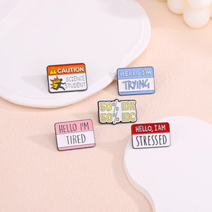 Set of five colorful enamel pins with English quotes on a minimalist display