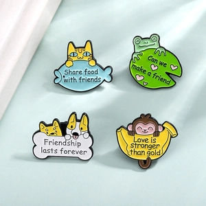 Detail view of four colorful enamel animal pins on a soft green fabric background