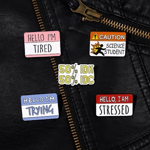 Close-up of five colorful enamel pins with slogans on a black leather jacket background