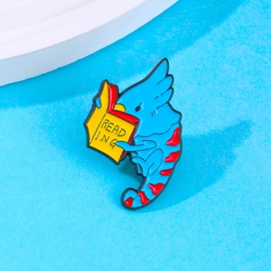 Close-up of a blue parrot enamel pin reading a book with fine detail and vibrant colors