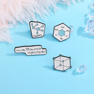 Detailed close-up of science chemistry enamel pins with chemical formulas on light blue base