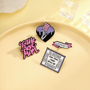 Set of four Mother's Day enamel pins with heart, ribbon, and stamp designs on a ceramic tray