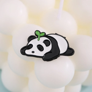 Vista macro di una simpatica spilla a forma di panda in smalto con germoglio verde e finitura