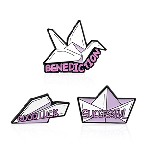 Three-piece purple enamel origami badges featuring crane, paper plane and boat shapes