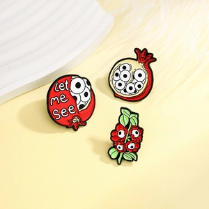 Three-piece surrealist pomegranate enamel pin set with creative eye design and floral shapes