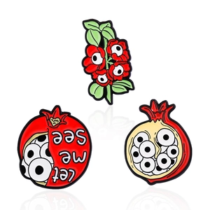 Three-piece pomegranate enamel pin set with surrealist eyes and 'let me see' text details