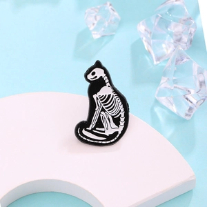 Creative black and white cat skeleton enamel pin brooch on a minimalist display stand