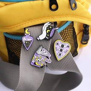 Set of four mystical enamel pins including magic potion and moon stars on a yellow backpack