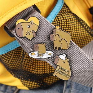 Set of four cute cartoon capybara enamel pins displayed on a backpack strap