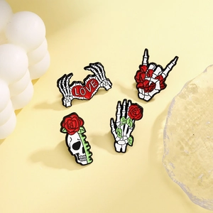 Set of four punk-style skull and rose enamel pins with skeletal hand gestures and hearts