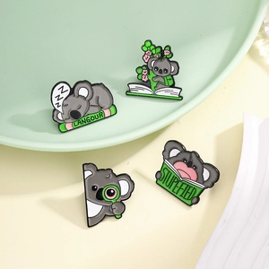 Set of four cute koala enamel pins featuring sleeping and reading designs in soft green