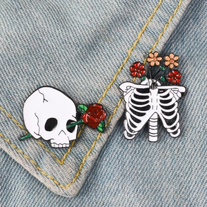 Gothic skull and ribcage enamel pins with roses on a blue denim jacket background