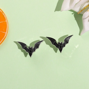 Gothic black bat wing enamel brooches set for Halloween outfits on green background