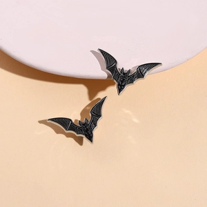 Gothic black bat enamel pin with silver wing details on soft peach background