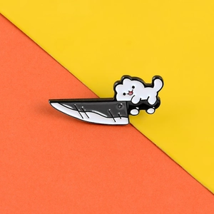 Creative enamel pin featuring a white cartoon cat climbing a black knife on a yellow backdrop