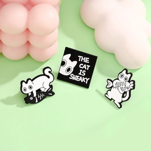 Three-piece black and white enamel cat and fish bone brooch set on green background