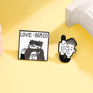 Λεπτομέρεια από την καρφίτσα σμάλτου Love Birds και την καρφίτσα φωτογράφου σε μαύρο και λευκό