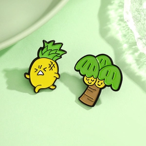 Détail de broches en émail représentant un espiegle ananas et un cocotier sur fond vert