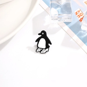 Détail de la broche pingouin en émail avec finition brillante sur un fond texturé chic
