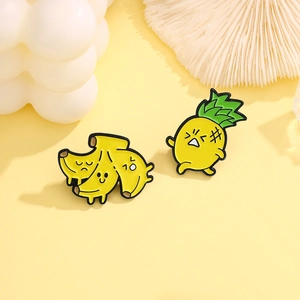 Détail des épingles en émail de banane et d'ananas de dessin animé sur un fond jaune vif
