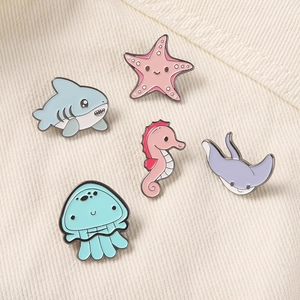 Cinque simpatiche spille smaltate con animali marini come squali e meduse su maglia