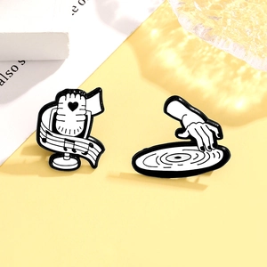 Close-up of creative black and white enamel pins with microphone and DJ vinyl record designs