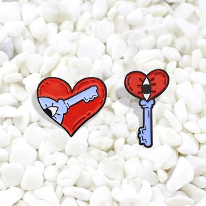 Creative red heart and blue key enamel pin set on a white pebble background for bags