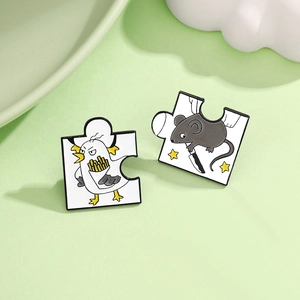 Detail of cartoon chick and mouse puzzle enamel pins on a fresh green background