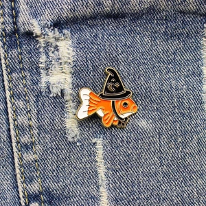 Pin's en émail poisson rouge magicien avec chapeau de sorcier sur veste en jean bleue