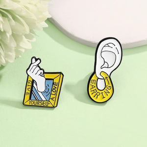 Creative enamel pin set featuring a yellow heart frame and an artistic ear with a hoop earring