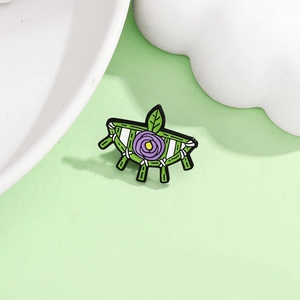 Close-up of alloy enamel pin featuring cartoon flower patterns and green fringe detail