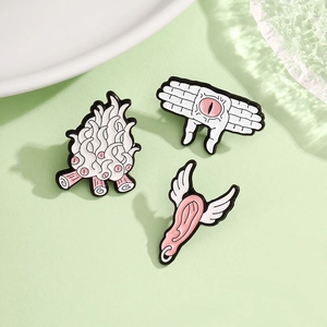 Macro detail of quirky enamel badges featuring winged ear and multi-eyed flame designs