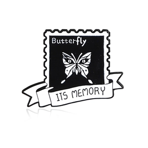 Detail of a vintage stamp enamel pin featuring a butterfly and its memory ribbon text