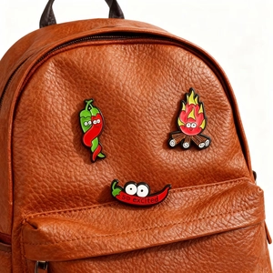 Creative chili and dragon fruit flame enamel pin set on a brown leather backpack