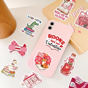 Detail of cute Bookish Valentine stickers applied on a pink phone case and book cover
