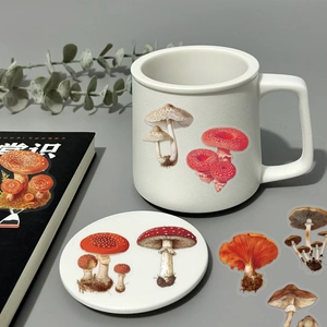 Macro shot of vintage mushroom stickers and a ceramic mug on a minimalist desk set