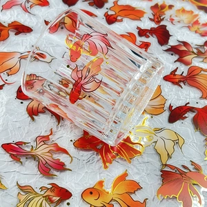 Macro view of transparent glass cup with gold-stamped koi fish stickers and relief stripes