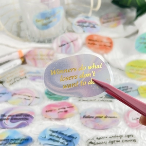 Macro shot of gold foil stickers with inspirational quotes on colorful marble patterns