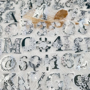 Detailed view of silver stamped floral alphabet and number stickers on PET material