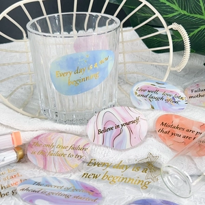 Detail of waterproof gold-foil quote stickers applied to a glass and notebook