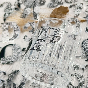 Detail of floral letter P silver foil sticker on a textured transparent glass cup