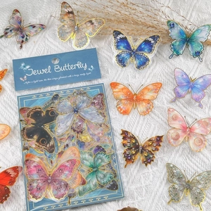 Close-up of vibrant butterfly stickers with gold foil edges on a white lace fabric background