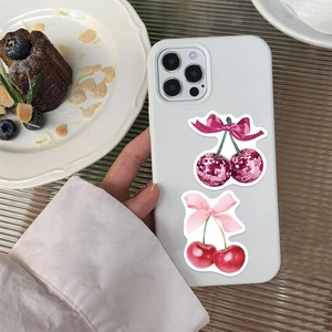 Coque de téléphone blanche avec illustrations de cerises et nœud rose sur table