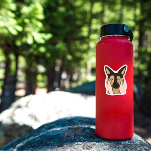 Detail of a cartoon German Shepherd waterproof sticker on a red metal thermal bottle