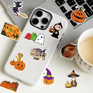 Halloween pumpkin stickers on a phone case next to a laptop and a coffee cup