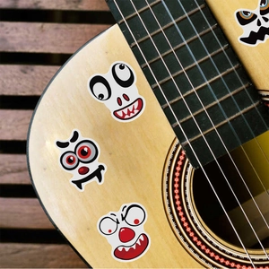 Waterproof cartoon monster face stickers applied on a wooden guitar for creative decoration
